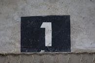 A weathered concrete wall with a bold number one painted on a black rectangular background.